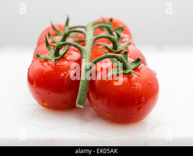 Frais mûrs tomates humide sur la vigne sur le marbre blanc. Profondeur de champ. Banque D'Images
