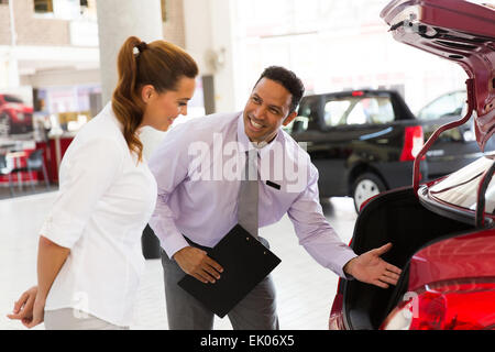 Beau vendeur de voiture montrant nouveau véhicule au client Banque D'Images