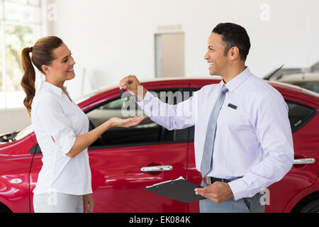 Jolie jeune femme qui reçoit la clé de voiture concessionnaire Banque D'Images