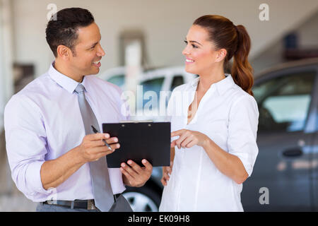 Deux heureux car sales consultants travaillant à l'intérieur d'exposition de véhicules Banque D'Images