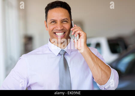 Mid age man talking on smart phone at car dealership Banque D'Images