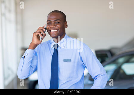 African American car salesman talking on cell phone in showroom Banque D'Images