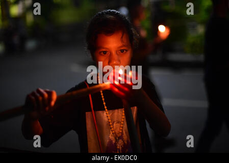 Larantuka, Indonésie. 3rd avril 2015. Un enfant allume une bougie pour préparer une marche de quatre heures dans la célébration du Vendredi Saint à Larantuka, sur l'île de Flores, en Indonésie. Des milliers de personnes, y compris celles d'autres villes et pays, assistent à des cérémonies d'une semaine entière pour célébrer la semaine sainte dans la petite ville de Larantuka, l'une des villes les plus influentes d'Indonésie en termes de traditions catholiques romaines. Banque D'Images