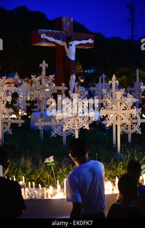 Larantuka, Indonésie. 3 avril 2015. Les gens prient dans un cimetière catholique romain après la cérémonie de masse à l'église de la cathédrale voisine lors de la célébration du vendredi Saint à Larantuka, île Flores, Indonésie. Des milliers de personnes, y compris celles d'autres villes et pays, assistent à des cérémonies de la semaine entière pour célébrer la semaine Sainte dans la petite ville de Larantuka, l'une des villes les plus influentes d'Indonésie en termes de traditions catholiques romaines. Banque D'Images