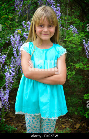 Une jeune fille pose en face de fleurs pour un printemps photo Banque D'Images