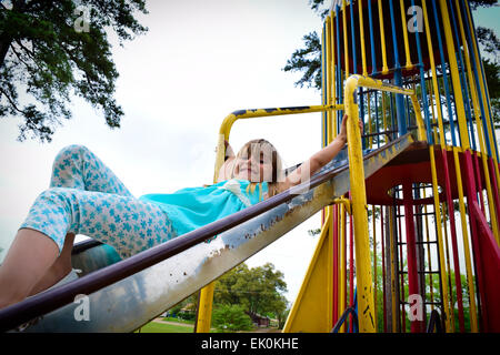 Une jeune fille glissant sur une diapositive à Kilgore City Park, Texas. Banque D'Images