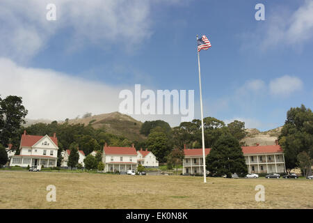 Ciel bleu nuages blancs sur place d'herbe avec le drapeau américain, à d'anciens bâtiments de l'armée, Fort Baker, San Francisco Banque D'Images