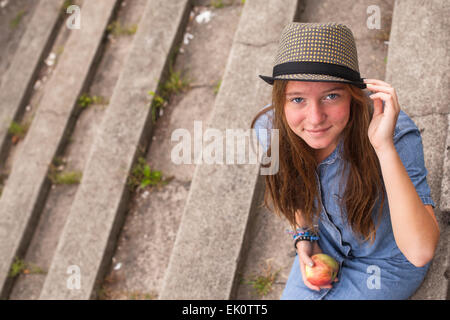 Jeune fille assise sur les marches de pierre de l'ancien parc. Banque D'Images