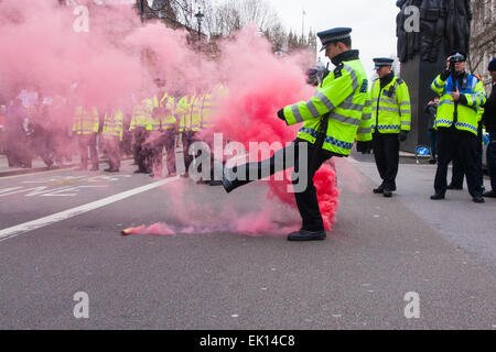 Whitehall, Londres, 4 avril 2015. Comme PEGIDA UK détient un mal à rallier sur Whitehall, des dizaines de policiers sont appelés à contenir des contre-manifestants de divers mouvements anti-fasciste de Londres. Sur la photo : un policier à coup d'une bombe fumigène jeté par les anti-fascistes, car ils tentent de briser les lignes de la police d'attaquer les quelques hommes et femmes qui fréquentent le PEGIDA rally. Crédit : Paul Davey/Alamy Live News Banque D'Images