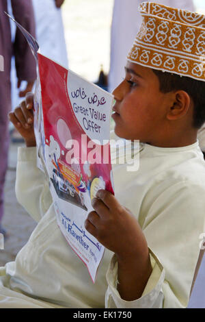 Boy reading supermarché, publicité Sinaw, Oman Banque D'Images