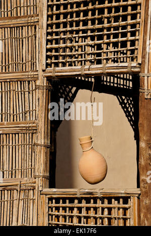 La poterie cruche d'eau suspendues dans des abris à bois fenêtre grillagées, Fort Nizwa Nizwa, Oman, Banque D'Images