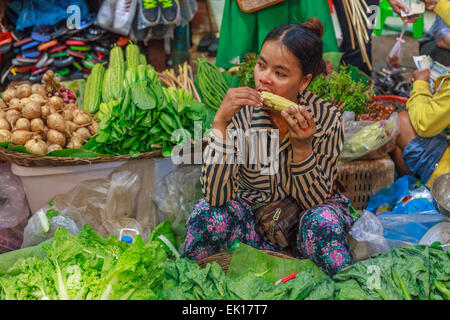 Young woman eating a s/n tout en vendant des légumes frais (Siem Reap) Banque D'Images