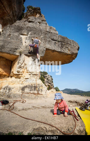 Bébé Garçon jouant au pied de la montagne tandis que sa mère monter à l'arrière-plan. Le garçon est liée à la corde. Banque D'Images