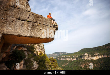 Jeune homme assis pensif sur le bord de la falaise Banque D'Images