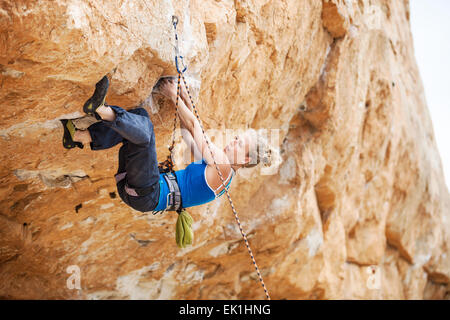 Young female rock climber luttant pour rendre la circulation vers le haut Banque D'Images