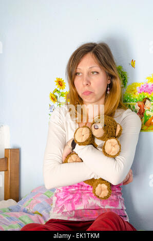 Sad girl hugging son ours en peluche sur le lit Banque D'Images