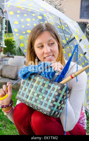 Girl smiling sous parapluie de couleur avec son tricot tools Banque D'Images