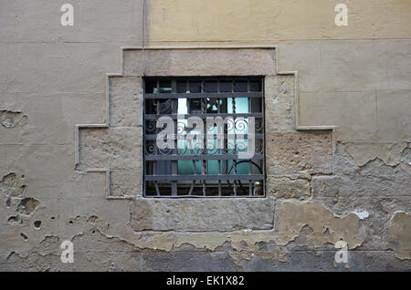 Fenêtre avec grille métallique de bars dans vieux mur de pierre de la rue arrière dans El Raval, Barcelone, Catalogne, Espagne Banque D'Images