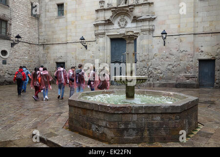 Groupe de jeunes touristes portant des imperméables en plastique sur jour de pluie sur la Plaça de Sant Felip Neri, quartier gothique, Barcelone Banque D'Images