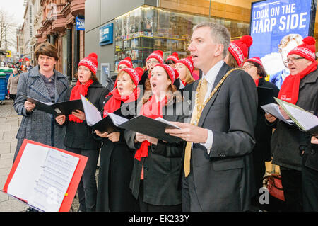 Belfast, Irlande du Nord. 12 Dec 2013 - Le ministre de l'Industrie et du Commerce, Arlene Foster, et Lord Maire de Belfast, Máirtín ó Muilleoir, chanter des chants de Noël à l'extérieur de la nouvelle £1.82M Belfast Welcome Center, un centre d'information touristique pour les visiteurs de Belfast et l'Irlande du Nord. Banque D'Images