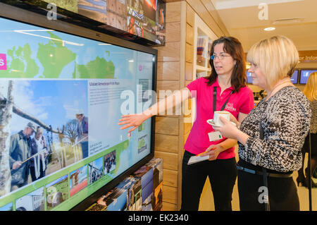 Belfast, Irlande du Nord. 12 déc 2013 - Un membre du personnel présente un visiteur le nouvel écran tactile interactif lors de l'ouverture du nouveau £1.82M Belfast Welcome Center, un centre d'information touristique pour les visiteurs de Belfast et l'Irlande du Nord. Banque D'Images