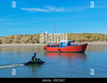 Le jeune homme s'approchant de jetski, plage de Barmouth, Gwynedd, au nord du Pays de Galles UK Banque D'Images