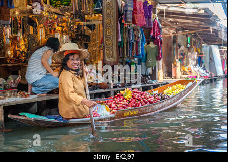 Femme thaïlandaise vend des fruits à partir d'un bateau au marché flottant de Damnoen Saduak. Le marché flottant est une attraction touristique majeure. Banque D'Images