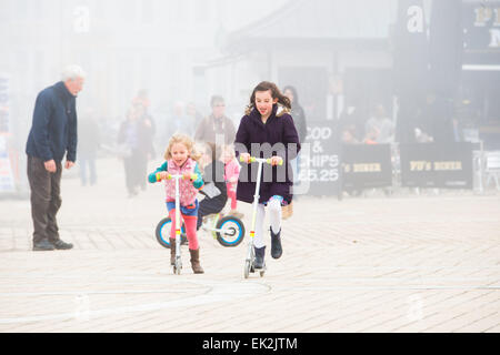 Aberystwyth, Pays de Galles, Royaume-Uni. 06 avril 2015. Après un brillant début, les brumes de la mer rouler dans plus de Aberystwyth sur Pâques lundi matin. Malgré le froid de l'air brumeux, les enfants en vacances race leurs trottinettes le long de la promenade et la jetée en dépit de cela, le beau temps devrait se maintenir pour les prochains jours, en particulier dans l'ouest du Royaume-Uni, avec des températures qui atteignent 19-20ºC dans des lieux Crédit : Keith morris/Alamy Live News Banque D'Images