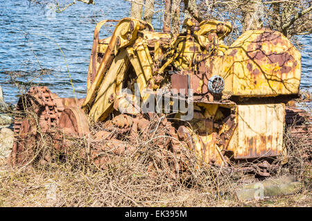 Abandonné et survécu bulldozer jaune crawler. La nature est d'essayer de le couvrir de végétation. Mer en arrière-plan. Beaucoup de rouille Banque D'Images