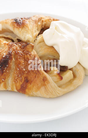 Strudel aux pommes pâtisserie danoise rempli de pomme et cannelle et raisins servi avec de la crème fouettée Banque D'Images