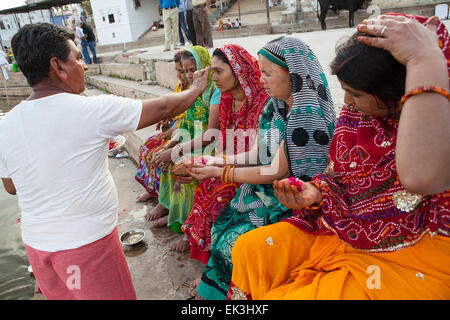 Un Pandit (prêtre et saint homme qui accomplit des cérémonies) mène des puja (prière) avec les pèlerins sur les ghats à Pushkar Banque D'Images