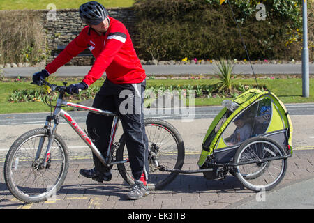 L'homme à casque vélo remorquage avec jeune enfant aussi casque de vélo à l'intérieur Banque D'Images