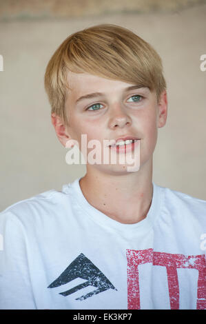 Un adolescent blond dans un blanc t shirt socialise à la table de cuisine Banque D'Images