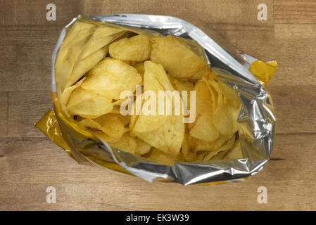 Croustilles de pommes de terre dans un sac ouvert sur une table en bois Banque D'Images