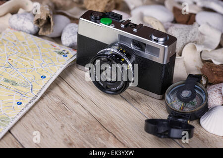 Dans l'image d'un film de caméra analogique , une boussole et une carte, sur les côtés des coquillages et pierres décoratives . Banque D'Images