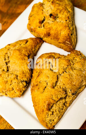 Cannelle et raisins fraîchement cuits sur un carré blanc scones plate Banque D'Images