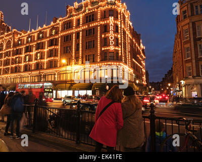 Touristes regardant le grand magasin Harrods illuminé la nuit, Brompton Road, Knightsbridge, Royal Borough of Kensington et Chelsea, Londres, Angleterre Banque D'Images