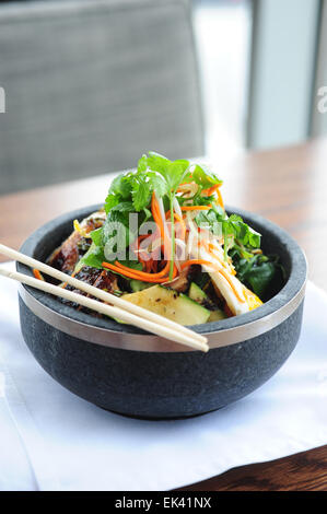 USA Food coin Asiatique style chicken rice bowl dans un restaurant fusion servi avec légumes marinés à la coriandre et baguettes Banque D'Images