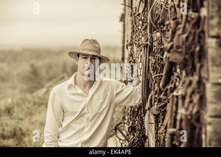 Portrait d'agriculteurs en face d'un mur plein avec de vieux outils rouillés Banque D'Images
