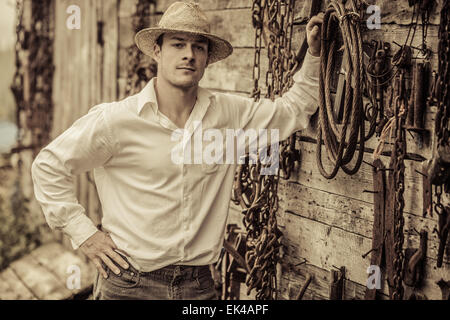 Portrait d'agriculteurs en face d'un mur plein avec de vieux outils rouillés Banque D'Images