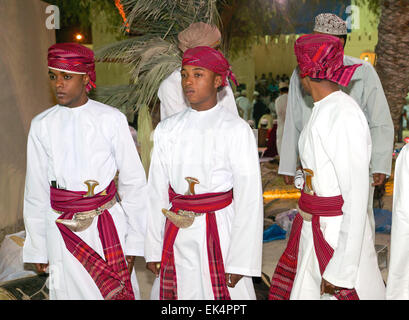 Trois jeunes hommes omanais en costume traditionnel, avec khanjars (poignards) arabe, à un festival culturel à Mascate, Sultanat d'Oman Banque D'Images