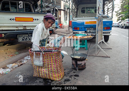 Vieux pauvre homme s'habiller en haillons se trouve par sa cuisine de rue mobile friteuse à Yangon Myanmar Banque D'Images