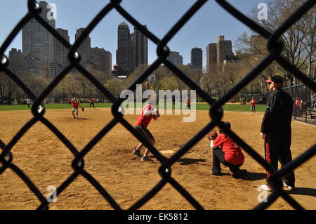 Les jeunes adultes jouer au baseball à l'Heckscher Ballfields dans Central Park, New York, vue à travers une clôture Banque D'Images