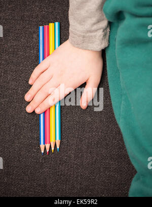 Little girl holding main au-dessus de crayons colorés. Banque D'Images