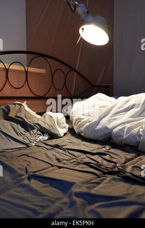 Draps et oreillers échevelée d'un lit défait, led lumière et moustiquaire Banque D'Images