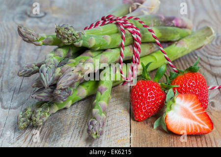 Les asperges vertes avec des fraises sur le sol en bois. Banque D'Images