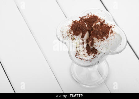 Verre de la crème glacée avec des copeaux de chocolat sur une table en bois blanc Banque D'Images