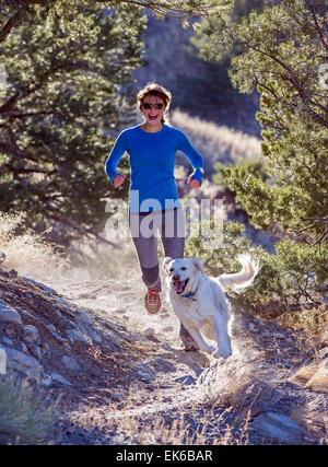 Belle jeune femme heureuse & chien qui court sur des sentiers de montagne près de Salida, Colorado, USA Banque D'Images