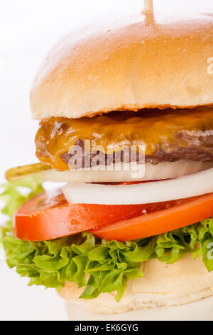 Savoureuse traditionnelle cheeseburger avec un sol recouvert de patty de boeuf fromage fondu et servi avec des oignons, tomates et bouclés Banque D'Images