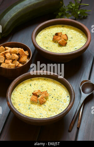 Deux bols rustiques de crème de courgettes soupe avec des croûtons en haut, photographiée en bois foncé avec lumière naturelle Banque D'Images